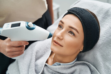 Cosmetician performing a face-lifting procedure with a CO2 mesotherapy gun