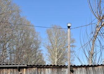 wooden support with diode soffit and wires. Rural landscape. homemade lighting pole with stretched...