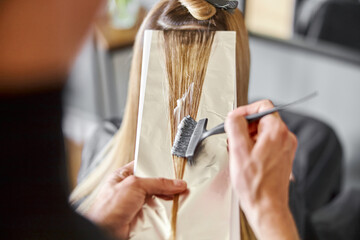 Naklejka premium Confident male stylist is dyeing hair of blond caucasian female client