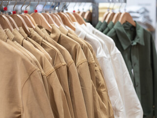 A display with clothes hanging on hangers in the store. Casual jackets for men and women.