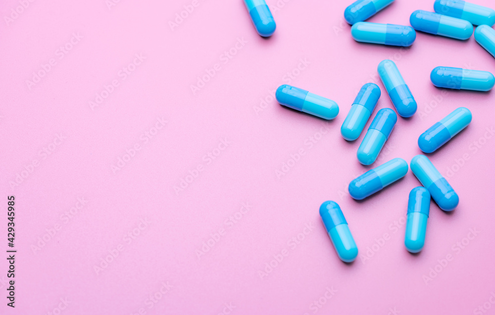 Wall mural blue capsule pills on pink background. blue capsule pills with copy space. pharmaceutical industry. 