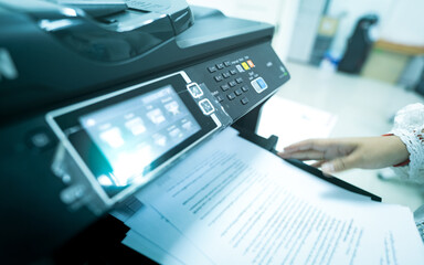 Office worker print paper on multifunction laser printer. Copy, print, scan, and fax machine in...