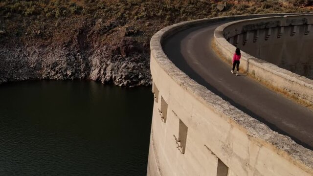 Aerial shot of an Asian woman hiking across the historic 100 year old Salmon Falls Dam in Southern Idaho