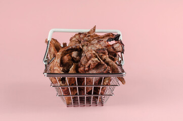 Shopping basket with dog treats on a pink background. Natural treats in a metal basket.