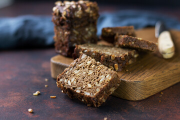 Grain bread cut into portions on a wooden stand. Close-up. Space for text