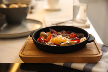 Tasty egg with vegetables in frying pan on wooden board