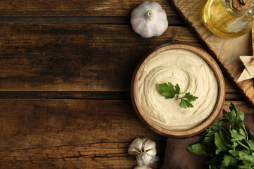 Delicious hummus with parsley on wooden table, flat lay. Space for text