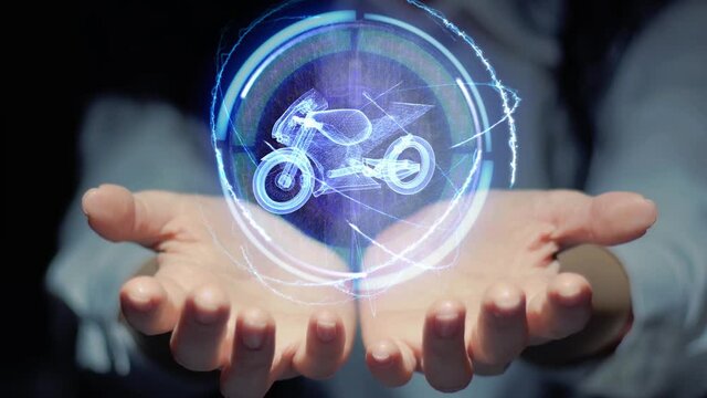 Female hands show a round conceptual hologram with modern sport bike. Unrecognizable woman in ashen white on a black background with future holographic technology