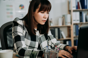 closeup asian businesswoman suffering blurred vision is squinting her eyes while working on the computer in the office.