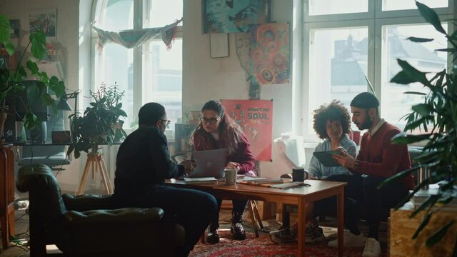 Team of Young Professionals Talking on a Meeting in Modern Creative Office. Diverse Team of Professionals Brainstorm, Share Data on Tablet Computer, Innovate, Chat, Solve Problems. Wide Shot