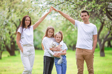 Fototapeta premium Adorable family in blooming cherry garden on beautiful spring day