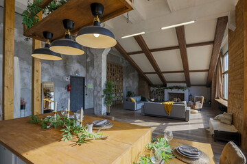 Dark loft style interior of big cozy country house. open plan apartment with kitchen area, rest zone and bed area. Huge windows and wooden decoration