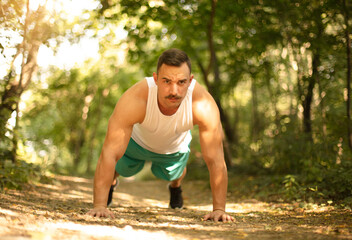 Obraz premium Man working push-ups in the forest.