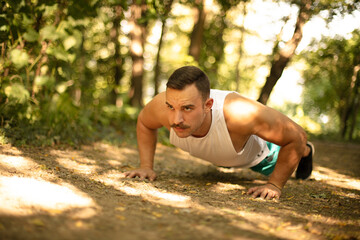 Obraz premium Man working push-ups in the forest.