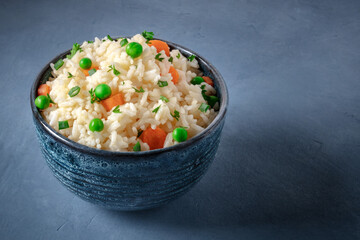 White rice with veggies on a blue background with copy space