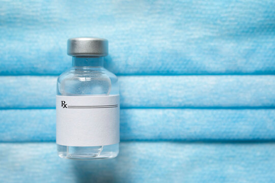 Medical vial of injectable medicine on a blue medical mask