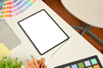 Designer workspace with digital tablets, coloured pencils and colour swatch on white desk