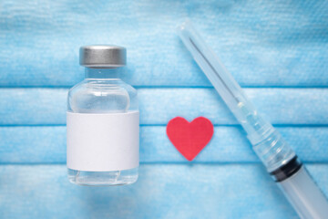 Medical vial of injectable medicine, syringe and paper red  hearton a blue medical mask