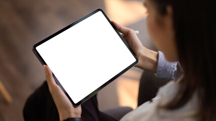 Cropped shot of young businesswoman looking at mock up tablet in office room