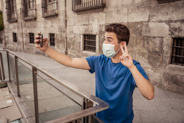 Young man wearing protective face mask video calling friends in the New Normal