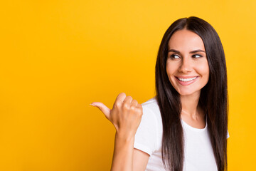 Photo portrait of funny girl wearing white t-shirt showing thumb blank space smiling isolated on vivid yellow color background