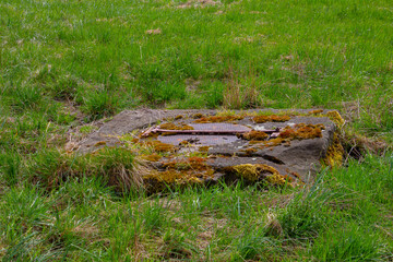 Close up of a old rusty metal square hatch in a grass field