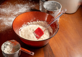 Leavened dough, a cup of flour and flour sifter on wooden table