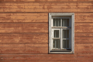 Old and shabby wall of wooden house with the window.