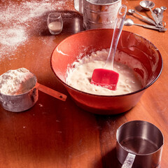 Leavened dough in a bowl with a cup of flour on wooden table