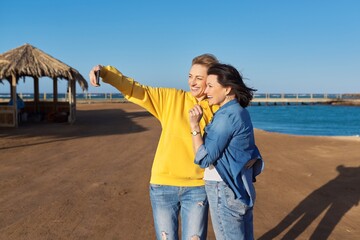 Two mature happy women taking selfie photo together using smartphone