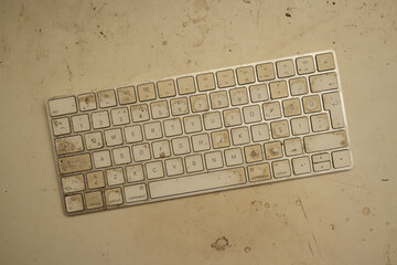 Very dirty wireless bluetooth keyboard on a dirty desk, top view