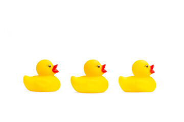Tres patos de goma en fila sobre un fondo blanco liso y aislado. Vista de frente y de cerca. Copy space