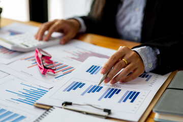 Close up of Business using calculator and laptop for doing math finance report on wooden desk, tax, accounting, statistics and analytical research concept