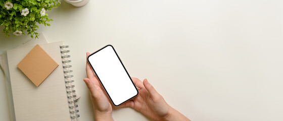 Top view of female hands holding smartphone on white workspace - Powered by Adobe