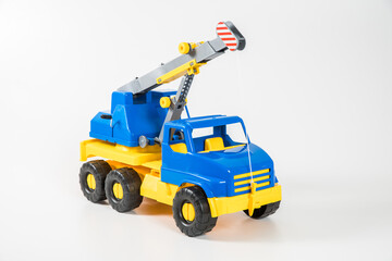 Plastic car. Toy model isolated on a white background. Yellow-blue truck crane with an arrow to lift the load.