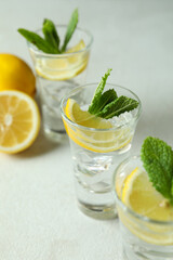 Shots with lemon slice and mint on white textured table