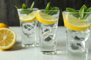 Shots with lemon slice and mint on white textured table