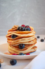 Freshly cooked delicious pancakes with honey, walnut, honey, raspberries and blueberries for breakfast.