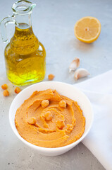 A bowl of delicious hummus with olive oil, garlic and paprika on a grey background.