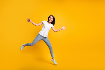 Full size photo of cute lovely young woman jump raise hands good mood isolated on yellow color background