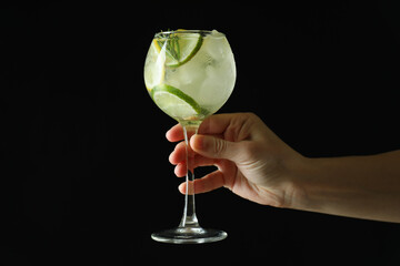 Female hand hold glass of cocktail with citrus on dark background - obrazy, fototapety, plakaty