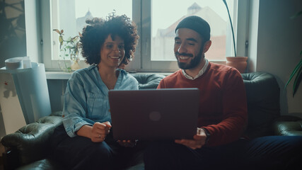 Two Young People Talk, Use Laptop Computer in Modern Creative Office. Business Team of Authentic Software Creators, App Developers, Marketing Specialists Brainstorm, Discuss Project. Medium Shot