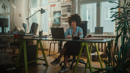 Creative Office: Young Black Woman Sitting at Her Desk Working on Computer. Charmingly Authentic Software Developer, Social Media Marketing Specialist Creating Content, Using Devices.