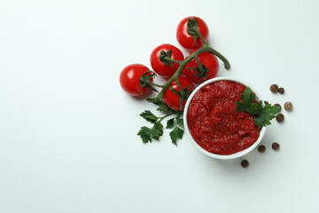 Bowl with tomato paste, tomatoes, pepper and parsley on white background
