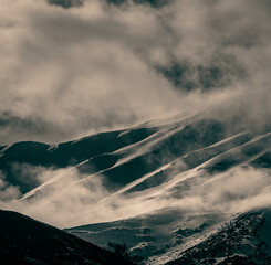 Monochromatic image of slopes of a snowy mountain. Clouds and mist over the slopes of Mt Etna 