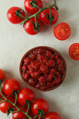 Wooden bowl with tomato paste and tomatoes on white textured table
