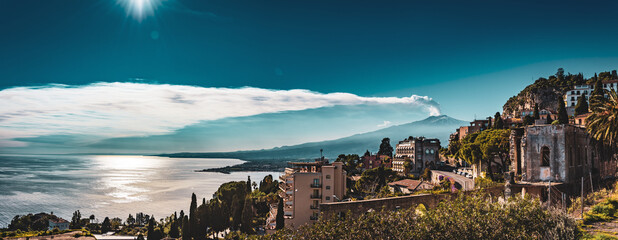 Panorama of Mount Etna smoking over the Mediterranean Sea, the city of Taormina in the foreground 