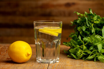 Water with sliced lemon on wooden background