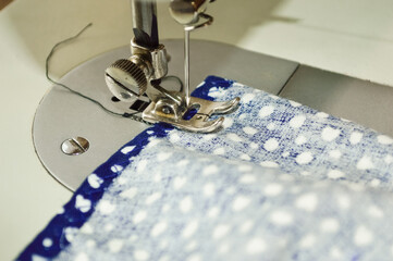 close-up - a piece of blue cloth is being sewn by a sewing machine