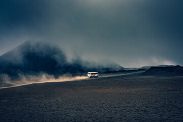 Shuttle bus leaving dust behind on the top of Mount Etna. Bus in the dessert, dramatic scenery 